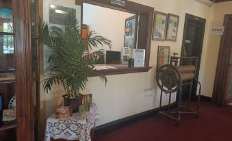 a room with a desk , a plant , and a window showing an elevator on the left side at Yanchep Inn