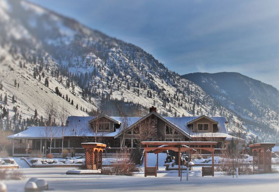 a snow - covered mountain with a large wooden cabin in the background , surrounded by snow - covered trees at Rocky Point Ranch