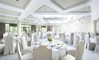 a large banquet hall with multiple round tables covered in white tablecloths and chairs arranged for a formal event at Parador de Cangas de Onis