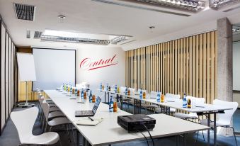 a conference room with a large table , chairs , and a central logo on the wall at Hotel Central