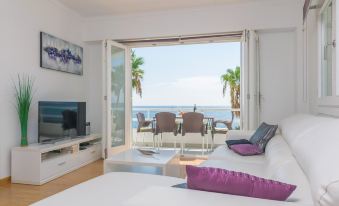 a living room with a couch , television , and sliding glass doors leading to an ocean view balcony at Hotel Cala Bona