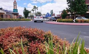 a busy city street with numerous cars parked on the side of the road , creating a lively atmosphere at Country Roads Motor Inn