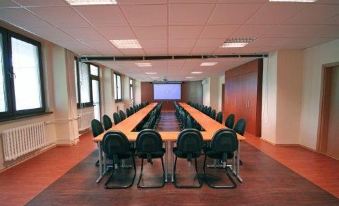 a large conference room with multiple rows of chairs arranged in a semicircle , and a projector screen mounted on the wall at Relax Inn