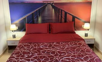 a bedroom with a bed and a mural of a bridge leading to a sunset at The Lux