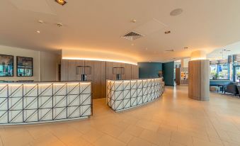 a modern hotel lobby with white marble reception desks , wooden walls , and a ceiling light at Crowne Plaza Reading