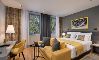 a modern hotel room with a yellow couch , black and white couch , wooden floors , and large windows at Hotel Ora