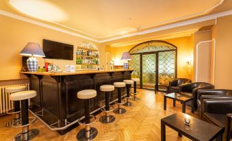 a modern bar with black furniture , wooden floors , and a large window , providing a comfortable atmosphere for patrons to enjoy drinks and socialize at Hotel Lindenhof
