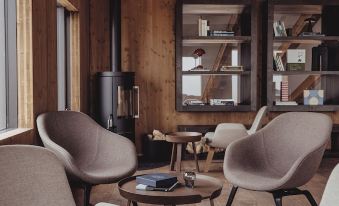 a cozy living room with wooden walls , a fireplace , and several chairs arranged around a coffee table at Highland Base Kerlingarfjoll