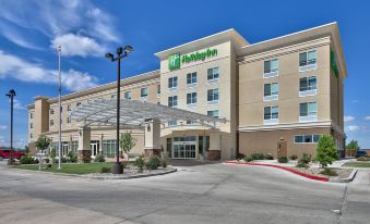 an exterior view of a hotel or motel , featuring a large parking lot and a clear blue sky at Holiday Inn Roswell