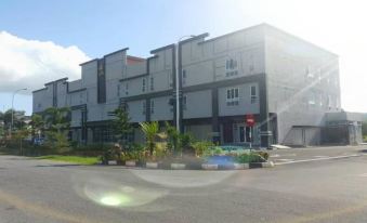 a modern building with a red sign on the front , surrounded by green plants and trees at Ants Hotel