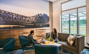 a man and a woman are sitting together in a modern lounge area , working on a laptop at Holiday Inn Express Kolkata Airport