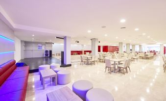 a large dining room with multiple tables and chairs , as well as a kitchen area at Mll Palma Bay Club Resort