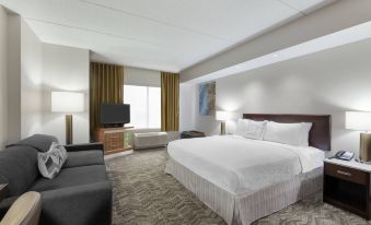 a large bed with white linens is in a room with a couch and television at SpringHill Suites Cleveland Solon