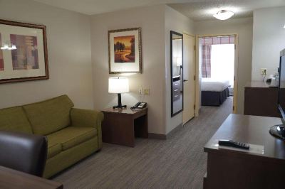 a living room with a green couch , wooden table lamp , and framed pictures on the wall at Country Inn & Suites by Radisson, Watertown, SD