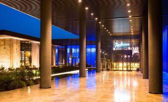 a modern hotel lobby with high ceilings , large windows , and stone floors , illuminated by lights at Radisson Hotel, Dakar Diamniadio