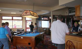 a group of people , including men and women , are gathered in a room with a pool table at Beauty Point Waterfront Hotel