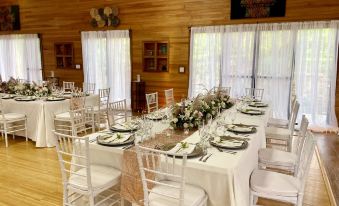 a long dining table set for a formal event , with white chairs and a wooden wall behind it at Dream Valley Belize