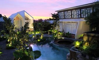 a serene backyard with a pool , lit up by lights , and surrounded by various plants and trees at Yats Colony