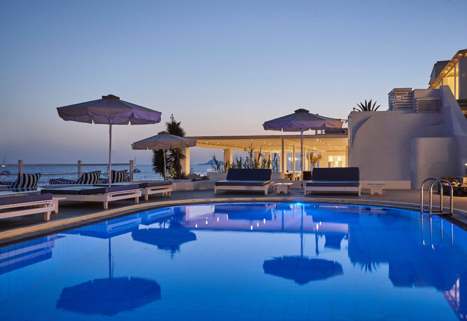 a large swimming pool with a few lounge chairs and umbrellas in front of a house at Notos Therme and Spa