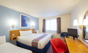 a modern hotel room with a blue and white theme , featuring a bed , a desk , and a chair at Travelodge Kendal