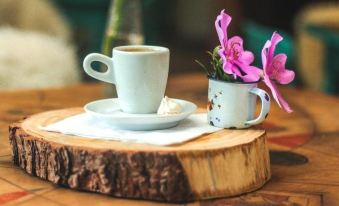 a wooden table with a cup of coffee and a plate of cookies , accompanied by a vase of flowers at Work Hotel