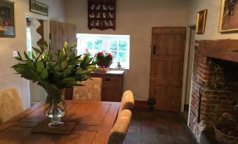 a dining room with a wooden table , chairs , and a vase of flowers on the table at Primrose Cottage