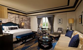 a luxurious hotel room with a king - sized bed , a couch , and a desk , all decorated in blue and white at Saratoga Casino Hotel