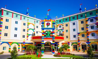 a large building with a colorful entrance and a clock tower is surrounded by greenery at Legoland® Florida Resort