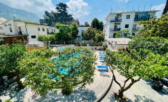 a beautiful outdoor pool area with trees , buildings , and buildings under a blue sky , under a clear sky at YourHome - Villa Sorrento