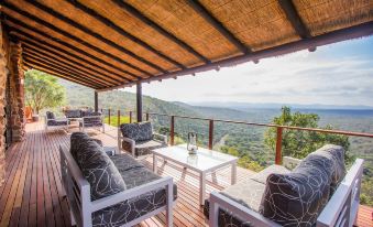 a patio with a view of the mountains , featuring several couches and chairs arranged for outdoor seating at Leopard Mountain Safari Lodge