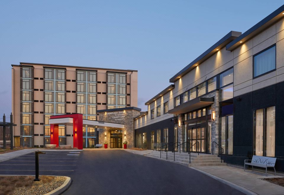 a large hotel building with a red mailbox in front , under a clear blue sky at Courtyard Oshawa