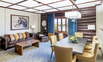 a living room with a wooden ceiling , a couch , a dining table , chairs , and a tv at Fairmont le Château Montebello