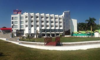 a large white building surrounded by a grassy field , with several chairs placed in front of it at Hotel Lake View