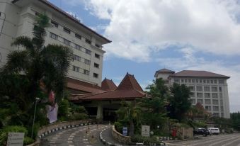 a large building with a red roof and several smaller buildings are visible in the background at The Sunan Hotel Solo