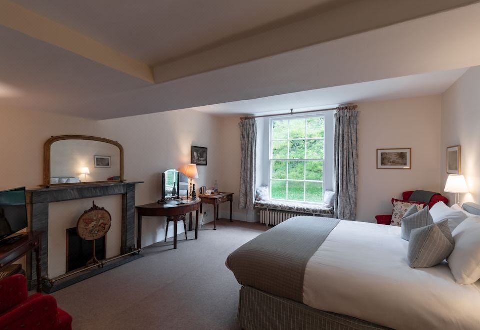 a cozy bedroom with a large bed , a fireplace , and a window overlooking a forest at Spread Eagle Inn