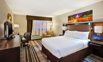 a large bed with white sheets and a brown headboard is in a hotel room at Holiday Inn Washington-Dulles International Airport, an IHG Hotel