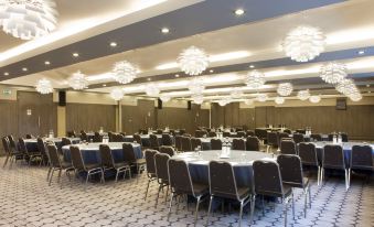 a large , empty banquet hall with multiple round tables and chairs set up for an event at Crowne Plaza London - Kingston