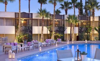 a hotel with a pool surrounded by palm trees , chairs , and tables for guests to enjoy their stay at Amman Marriott Hotel
