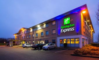 "a large building with the sign "" holiday inn express "" lit up at night , surrounded by cars parked in front of it" at Holiday Inn Express East Midlands Airport