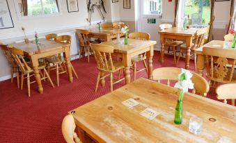 a dining room with wooden tables and chairs arranged for a group of people to enjoy a meal together at The Trout Inn