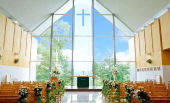 a church interior with wooden pews , a cross on the altar , and green plants lining the aisle at Arcadia