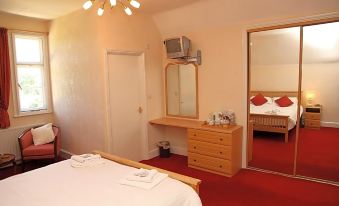 a hotel room with a red carpet , white walls , and a bed , along with a bathroom visible through an open door at The Red Lion