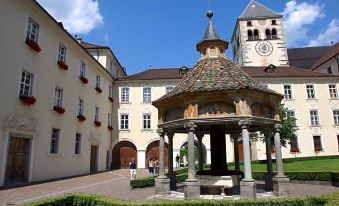 a beautiful courtyard with a gazebo and a church in the background , surrounded by lush greenery at Hotel Grüner Baum