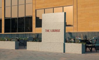 "a modern building with a large sign that reads "" the lounge "" prominently displayed on the side of the building" at Radisson Blu Hotel Buraidah