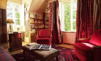a cozy living room with red curtains , wooden furniture , and books on a coffee table at The Good House