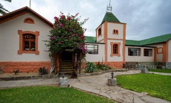 a large , pink building with a green roof and red walls is surrounded by grass and trees at Canyon Lodge