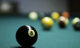 a black billiard ball with the number 8 on it is placed on a pool table , surrounded by other balls at Waterfall Resort