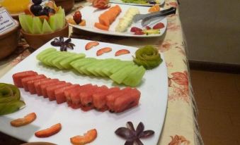 a dining table with a variety of sliced fruits , including apples , oranges , and grapes , arranged in a decorative manner at Hotel Midori