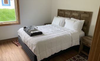 a neatly made bed with white sheets and pillows , accompanied by a wooden headboard and nightstand in a bedroom at Big Arm Resort