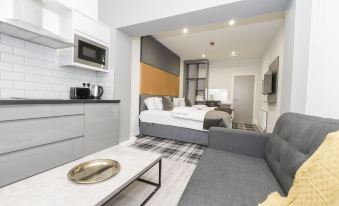 a modern living room with a gray couch , white coffee table , and a kitchenette in the background at 42 Apart-Hotel